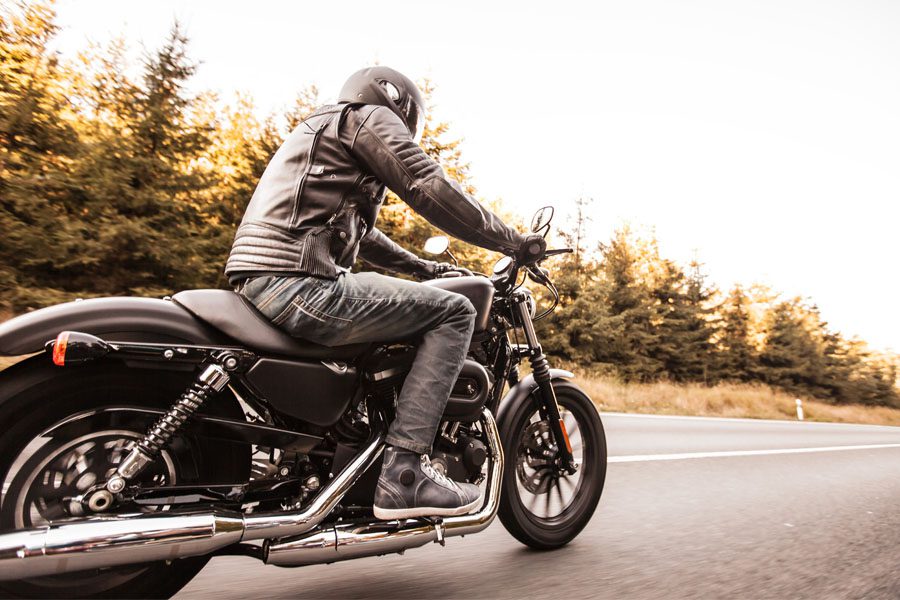 摩托车保险-男子骑摩托车沿松林路