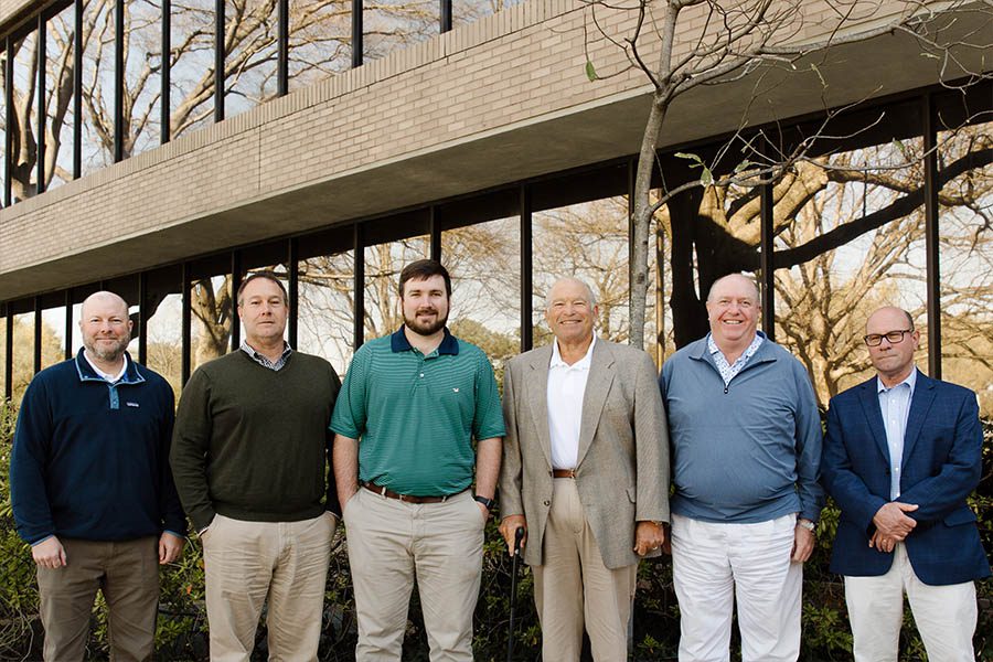MG游戏官方网站的机构-博伊尔保险机构的男性团队成员站在办公室前面，他们微笑着在一个美好的日子里合影